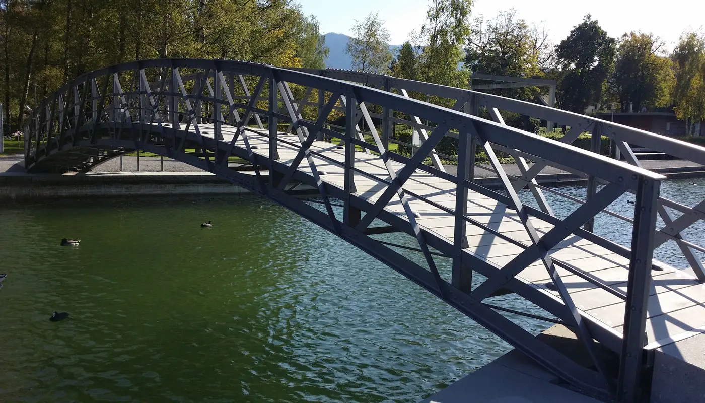 Uferpromenade Unterägeri
Die mehr als 100-jährige, denkmalgeschützte Stahlbrücke musste im Jahr 2013 umfassend instandgesetzt werden. Sie erhielt einen neuen Belag aus schlanken, kohlefaserbewehrten Betonbohlen, der die Auflast der Brücke reduziert.