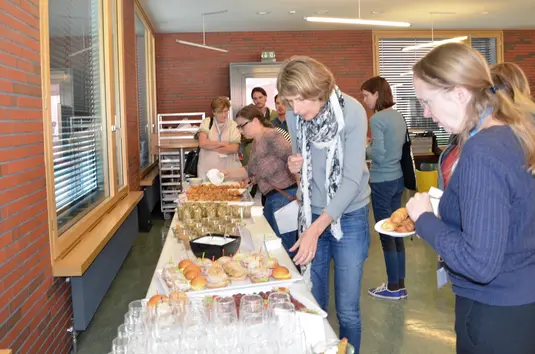 Cafeteria. Einige Konferenzteilnehmende bedienen sich am Mittagsbuffet.