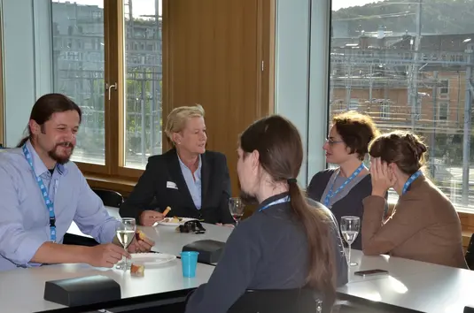 Apéro. Eine Gruppe von Konferenzteilnehmenden sitzt beim Apéro um einen Tisch.