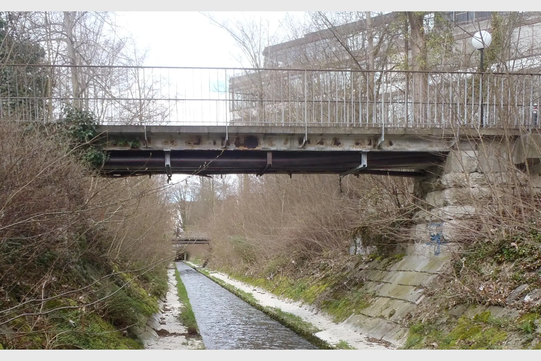 Sanierungsbedürftig: Die ursprüngliche Konstruktion aus zwei parallelen Stahlhauptträgern war durch Sickerwasser korrodiert. Auf den Trägern lag ein Betonbohlenbelag, die Geländerpfosten waren mit Konsolen an den Stegen der Träger verschraubt. Unter