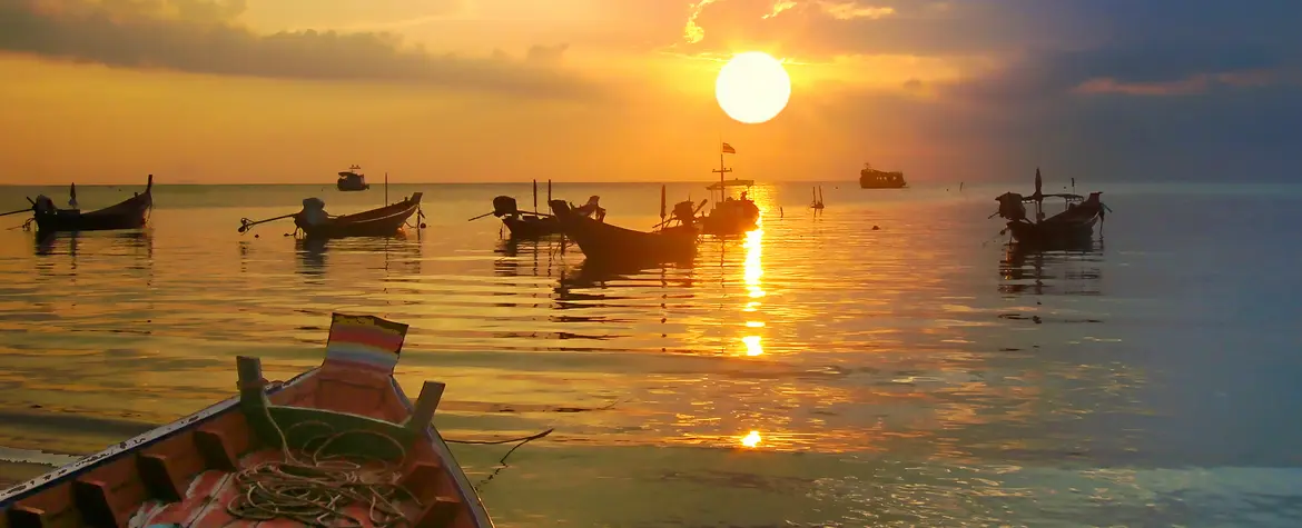 Bilder von thailändischen Kleinboten auf dem Meer während des Sonnenunterganges.