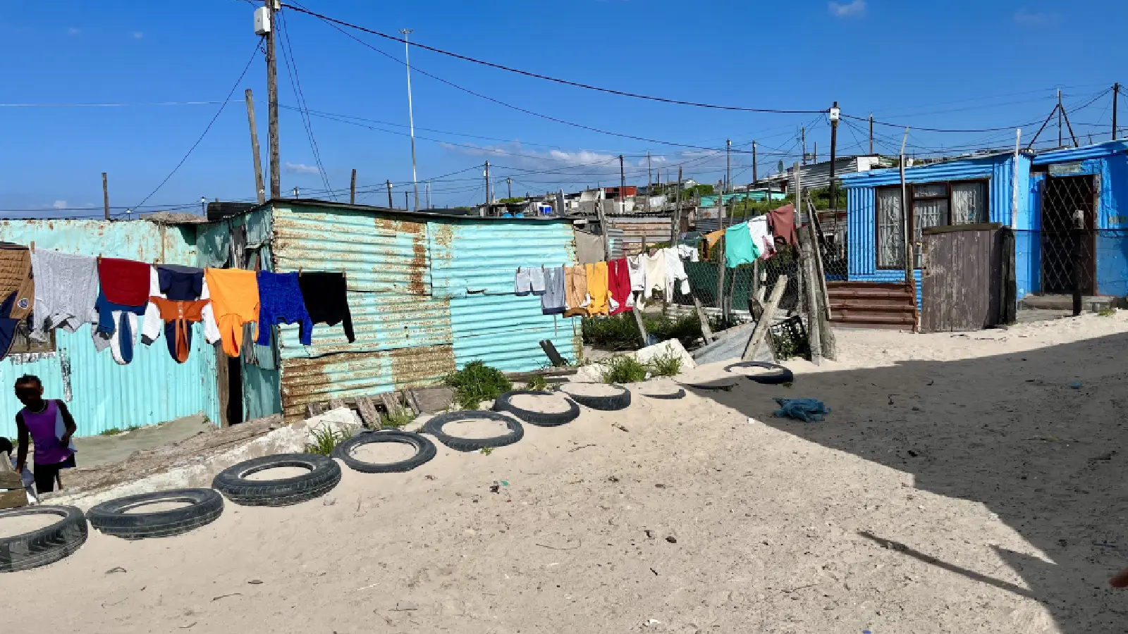 Shacks in the informal settlement, made of corrugated iron. Laundry is hung out to dry in front of them.